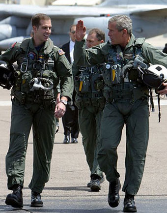 President George W. Bush in flight suit waving with a pilot walking next to him