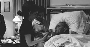 LBJ sipping through a straw while Lady Bird and Luci stand by his bed