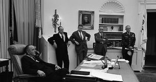 LBJ sitting down surrounded by aides