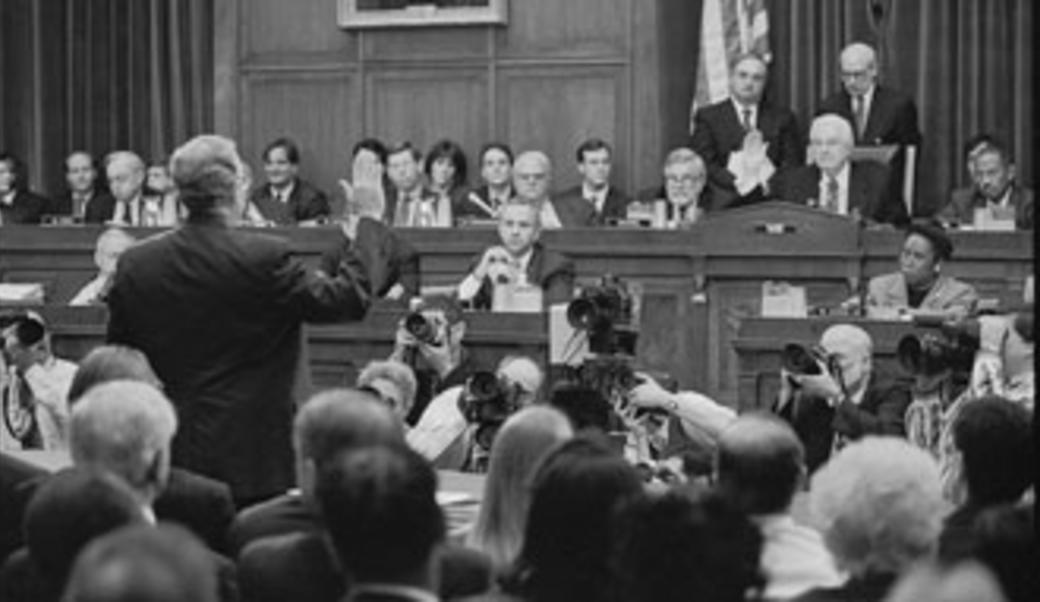 Black and white photo of Ken Starr with right hand raised.
