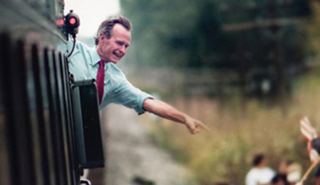 George H. W. Bush points from a train