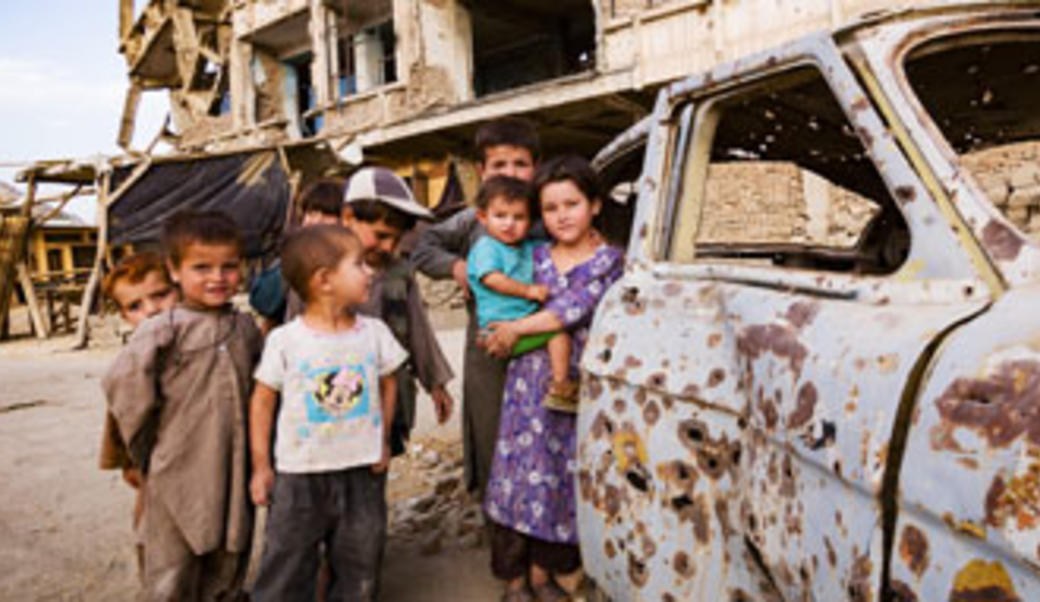 children next to bullet-riddled car